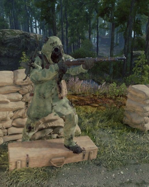 A Turned Soldier in a hooded hazmat suit aims a bolt-action rifle from behind sandbags in a forest