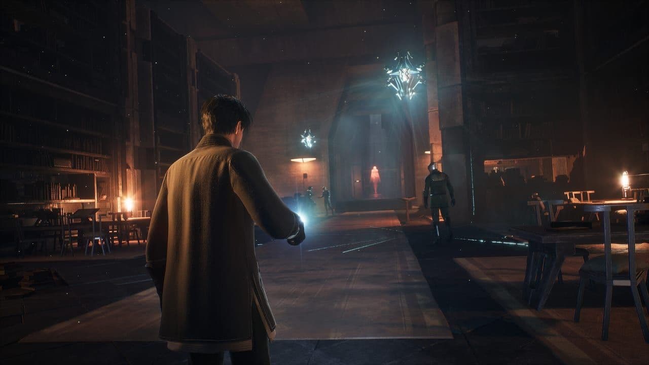 A figure in a dark coat stands in a shadowed hall lit by a single lamp in Dune: Awakening